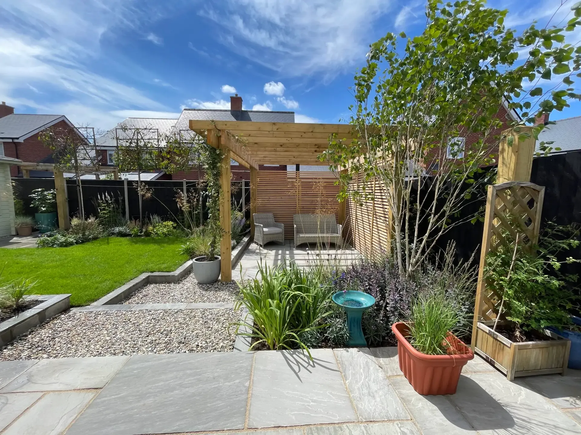 Contemporary family garden design in Beaulieu, Essex featuring a timber pergola, layered planting and pathways