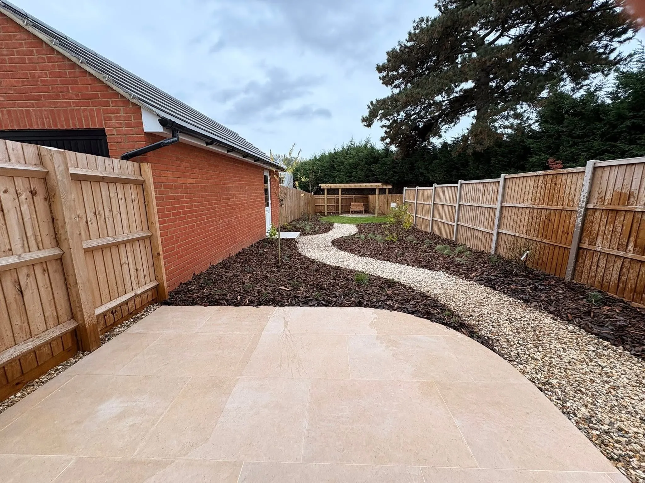 Timber pergola seating area framed by lawn and new planting in Kelvedon garden
